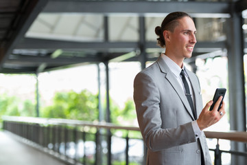 Fototapeta premium Portrait Of Young Handsome Businessman Using Phone Outdoors