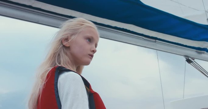 Portrait of cute 6 yo Caucasian girl sailing on yacht on a large lake. 4K UHD 60 FPS SLO MO