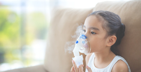 Cute Asian child  patient inhalation therapy by the mask of inhaler with soft stream smoke from bronchodilator. - obrazy, fototapety, plakaty