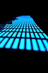 Luminous panel of pixels, with neon blue color and an equalizer on a black background