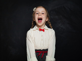 Happy Child Girl Laughing on Blackboard Background. Kid Creativity and Education Concept