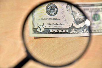 I look at a 5 dollar bill under a magnifying glass. The concept of verification for authenticity,...