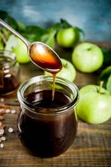 Home cooked dark salted classic caramel sauce, with green apples, wooden and dark blue background,