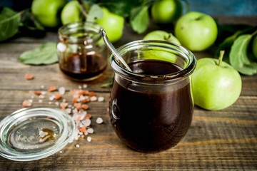 Home cooked dark salted classic caramel sauce, with green apples, wooden and dark blue background,