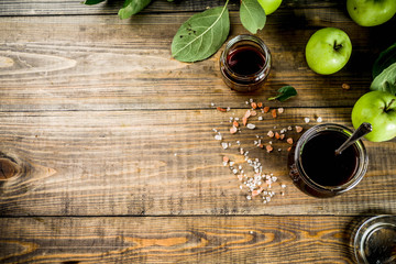 Home cooked dark salted classic caramel sauce, with green apples, wooden and dark blue background,