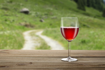 red wineglass on a wooden table with a country background