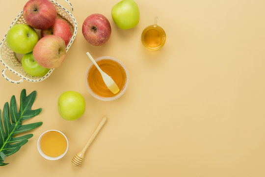 Table top view aerial image of decorations Jewish holiday Rosh Hashana background concept.Flat lay of variety apple & honey with green leave on modern rustic yellow paper.Free space for design text.