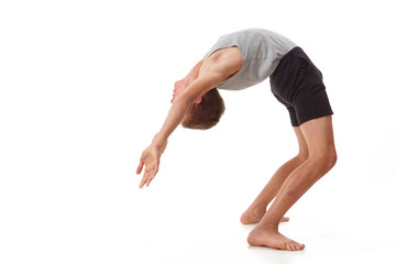 Teen in a T-shirt and shorts performs gymnastic exercises.