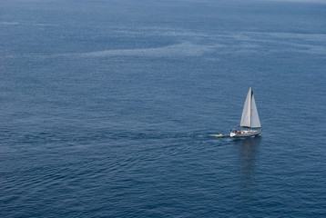 Sailboat sailing in the endless blue and quiet sea