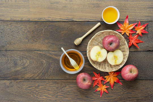 Table top view aerial image of decoration Fall harvest or Rosh Hashanah day background concept.Flat lay apple slice & honey bee with maple leave on modern rustic brown wooden.Copy space for add text.