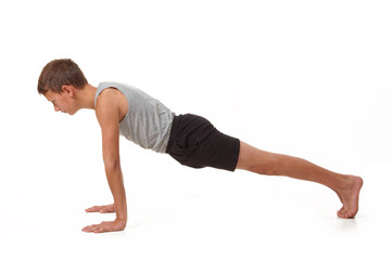 Teen in a T-shirt and shorts performs gymnastic exercises.
