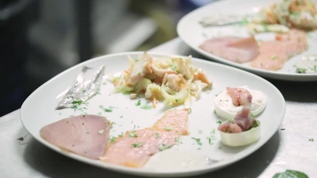 Antipasto di mare a base di pesce, impiattamento da parte dello chef nella cucina di un lussuoso ristorante.