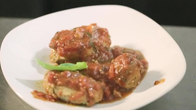 Polpette di pesce impiattate in un ristorante di lusso con basilico e olio extra vergine di oliva e sugo