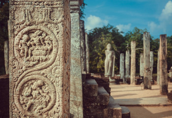 Carved stone columns and statue of Buddha at temple complex from 12th century, Polonnaruwa, Sri Lanka. UNESCO World heritage Site