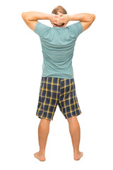 A man is standing with his back in his pajamas with his hands behind his head on a white background. Isolated.