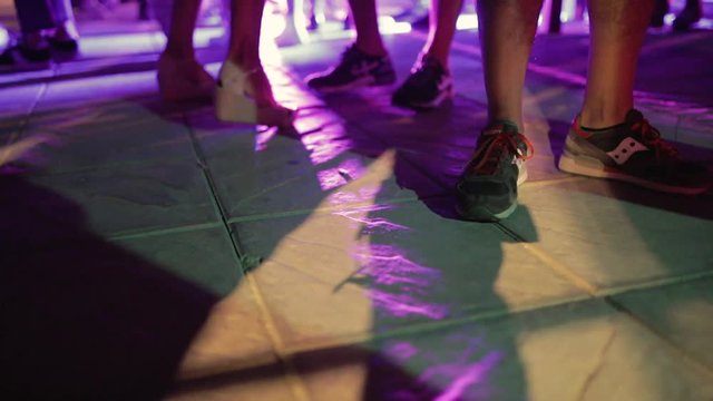 Piedi con scarpe e sandali estive di donne e uomini che ballano in una festa notturna, vista bassa.