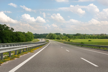 Almost emty asphalt highway with blue cloudys sky on background. Toll roads construction