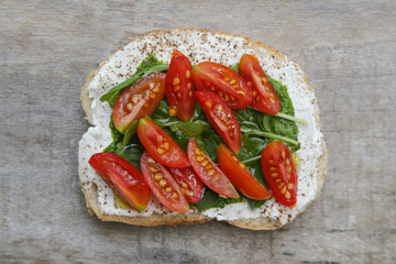 Top view of open sandwich with arugula and cherry tomato