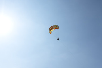 People on a parachute against the blue sky.
