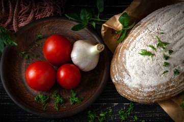 fresh baked bread with tomatoes and garlic with basil on a dark wooden background