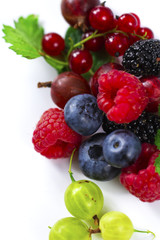 Close-up arrangement mixed, assorted berries including blackberries, strawberry, blueberry, raspberries and fresh leaf on white