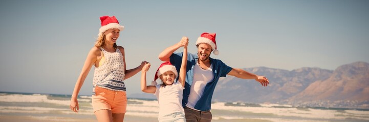 Happy family wearing Santa hat while enjoying at beach