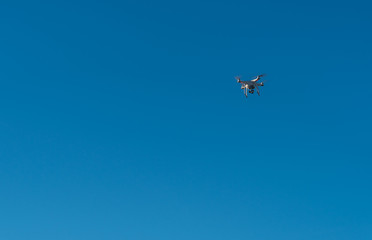 Modern Drone with camera flying on blue sky background.