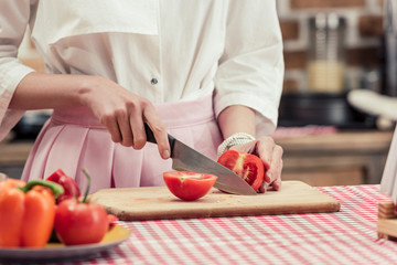 cropped shot of housewife in vintage clothes cutitng tomato