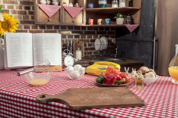 various uncooked products and recipe book on cooking table at kitchen
