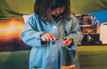 Una niña juega con pinturas y temperas