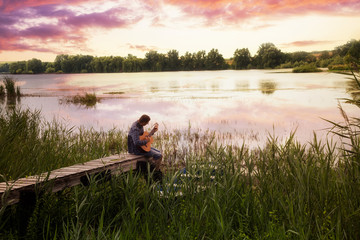 Mann spielt Gitarre am See