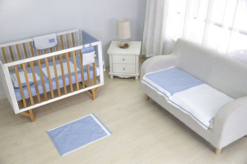 A mother's bedroom is filled with baby equipment. There is a changing mat and clothes sprawled over the bed.