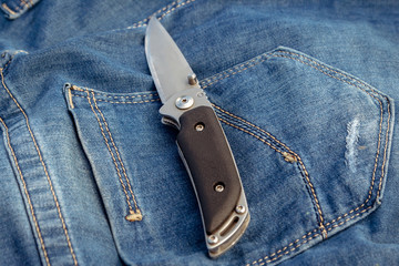 A sharp knife on a jeans background in nature.