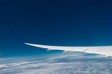 Wing of airplane flying above the clouds in the sky