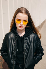 beautiful fashionable kid girl with long hair in yellow sunglasses in city,