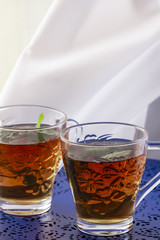 Two glasses of tea with fresh mint on the blue table