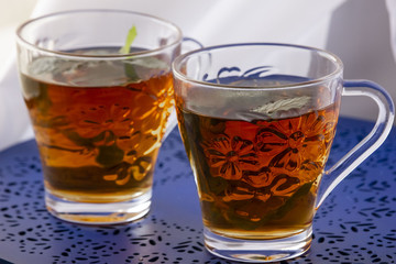 Two glasses of tea with fresh mint on the blue table