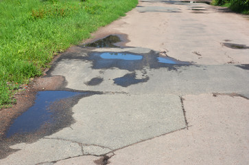 Asphalt  on puddles. Pot hole or pothole image of a broken cracked asphalt pavement with a dirty water puddle as a transportation symbol of road maintenance and car insurance risk to auto suspensions.