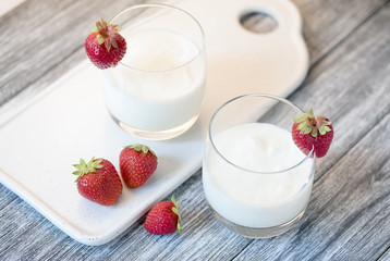 Yogurt with strawberry on wooden gray table.