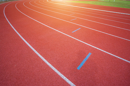 White lines of stadium and texture of running racetrack red rubber racetracks in outdoor stadium are 8 track and green grass field,empty athletics stadium with track.