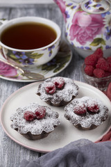 Cake with raspberries and sugar powder on the table with tea teapot.