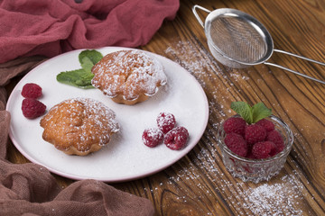 Capcake with raspberries and sugar powder on the table with tea teapot.