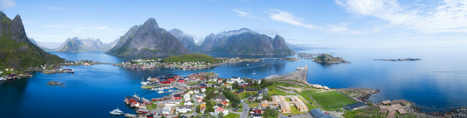 Beautiful aerial panorama of  the blue sea surrounding the fishing village  and rocky peaks Reine,...