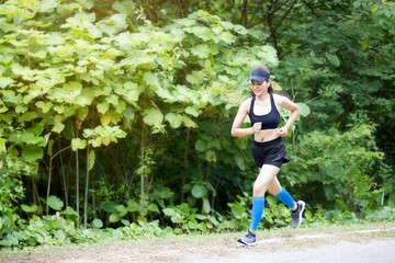 Asian woman were jogging on the road In the forest.wide angle copy space image.