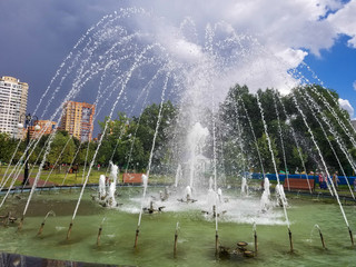 Water jets in fountain in city park in rainy weather.