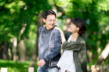 新緑の下でスキンシップをとるカップル