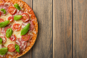 Pizza margarita on a wooden background, top view. Pizza Margarita with tomatoes, basil and Mozzarella cheese.