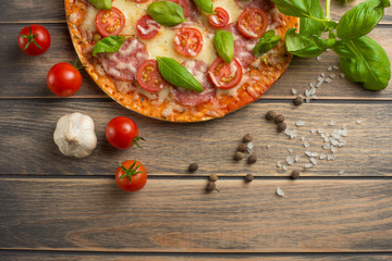 Pizza margarita on a wooden background, top view. Pizza Margarita with tomatoes, basil and Mozzarella cheese.