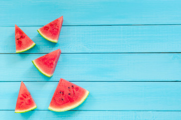 Top view of watermelon slices on a turquoise wooden background