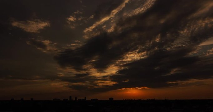 TIME LAPSE: Sunset behind moving clouds over small city